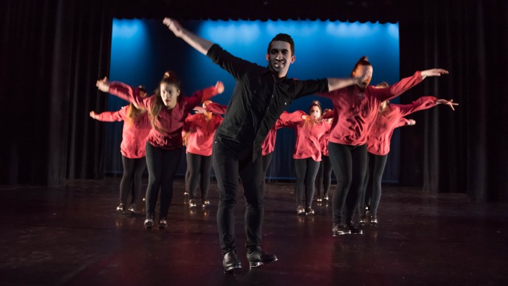 A group of students dancing with arms out during a tap dance performance.