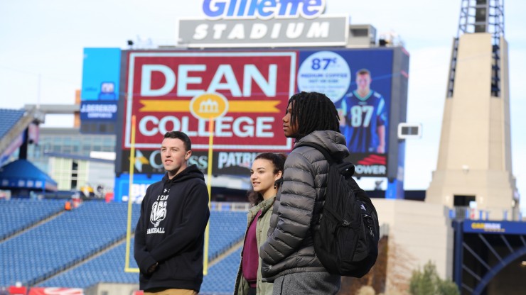 Three students standing on the football field at Gillette Stadium, home of the New England Patriots. 