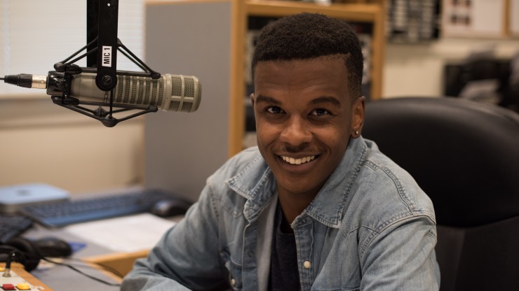 A student smiling at the camera in the Power88 radio station. 