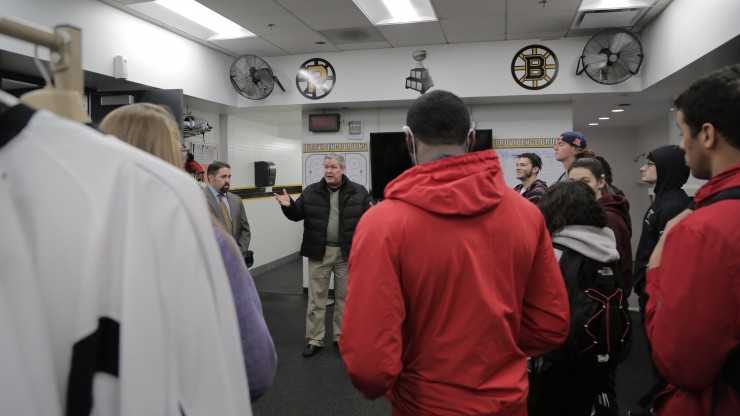 A professor speaks to a group of students in the Providence Bruins' locker room while on a tour of the Dunkin Donuts Center facilities. 