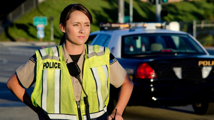 A police officer standing outside of a cop car.