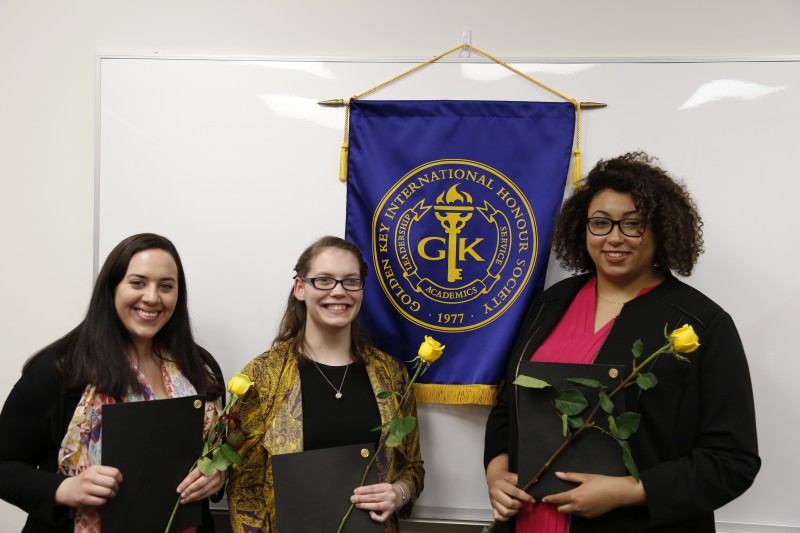 image of three students standing in front of banner during Golden Key International Honor Society event.