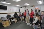 a professor speaking to a group of students in the locker room of the Providence Bruins while on tour of the Dunkin Donuts Center. 